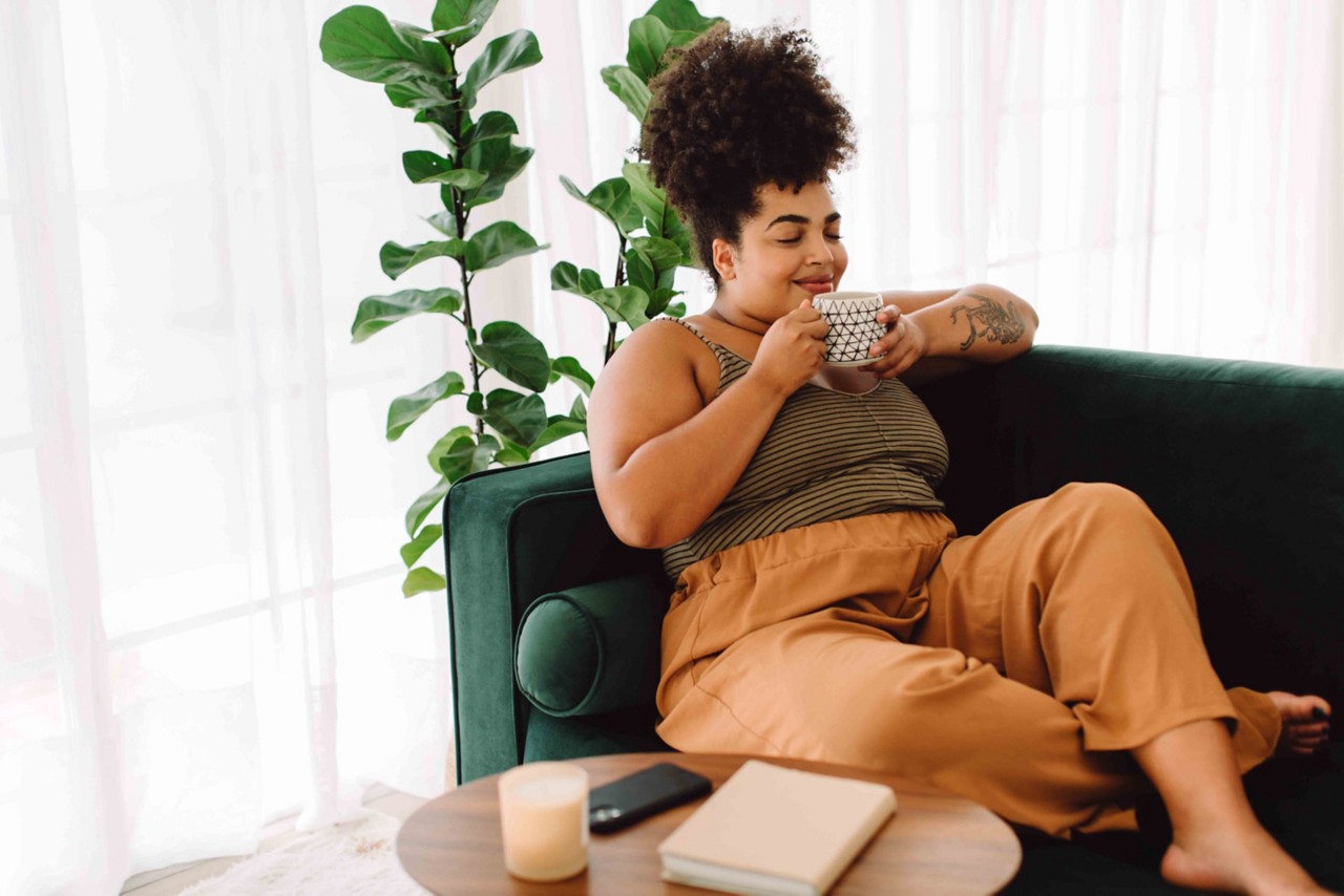 Person sitting on couch drinking tea.